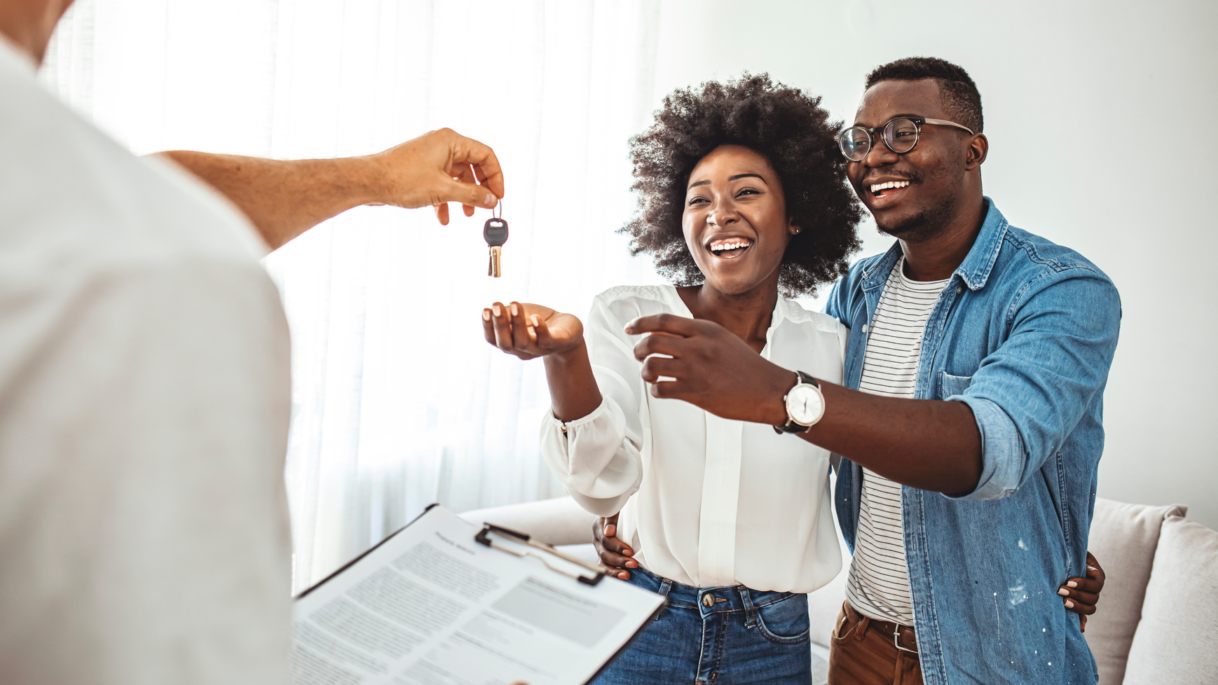 Couple Getting Keys From Real Estate Agent Of Their New Home.